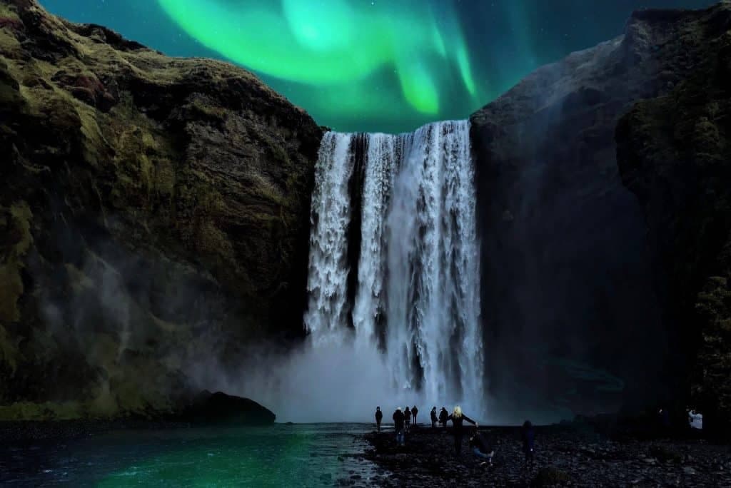 Northern lights behind famous waterfall in Iceland