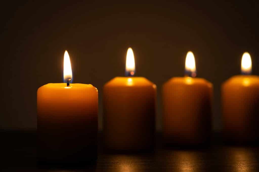 Group of lit candles in a row burning in the darkness